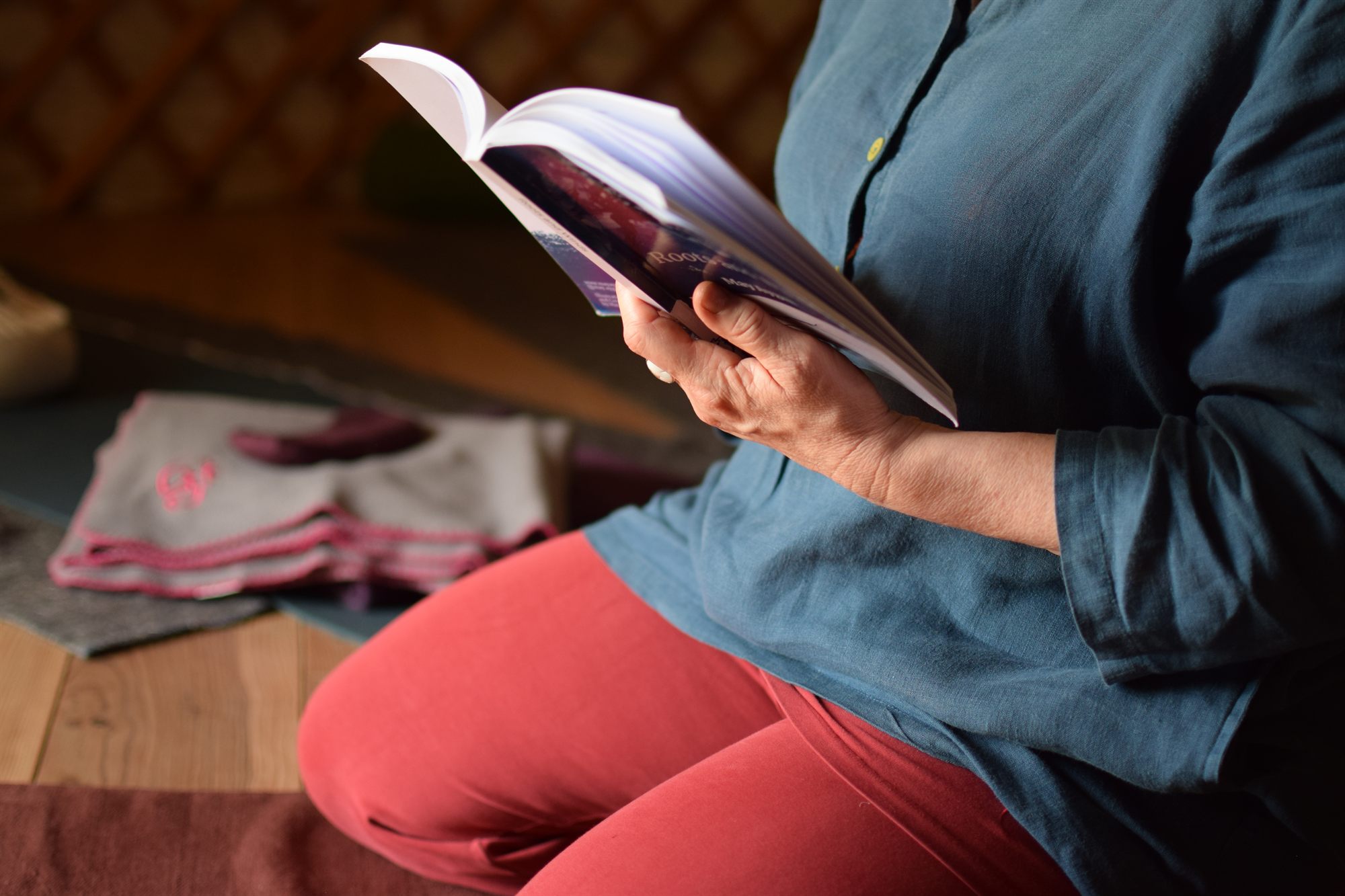 Patricia leest een dichtbundel, zittend op een meditatiekussen in de yurt