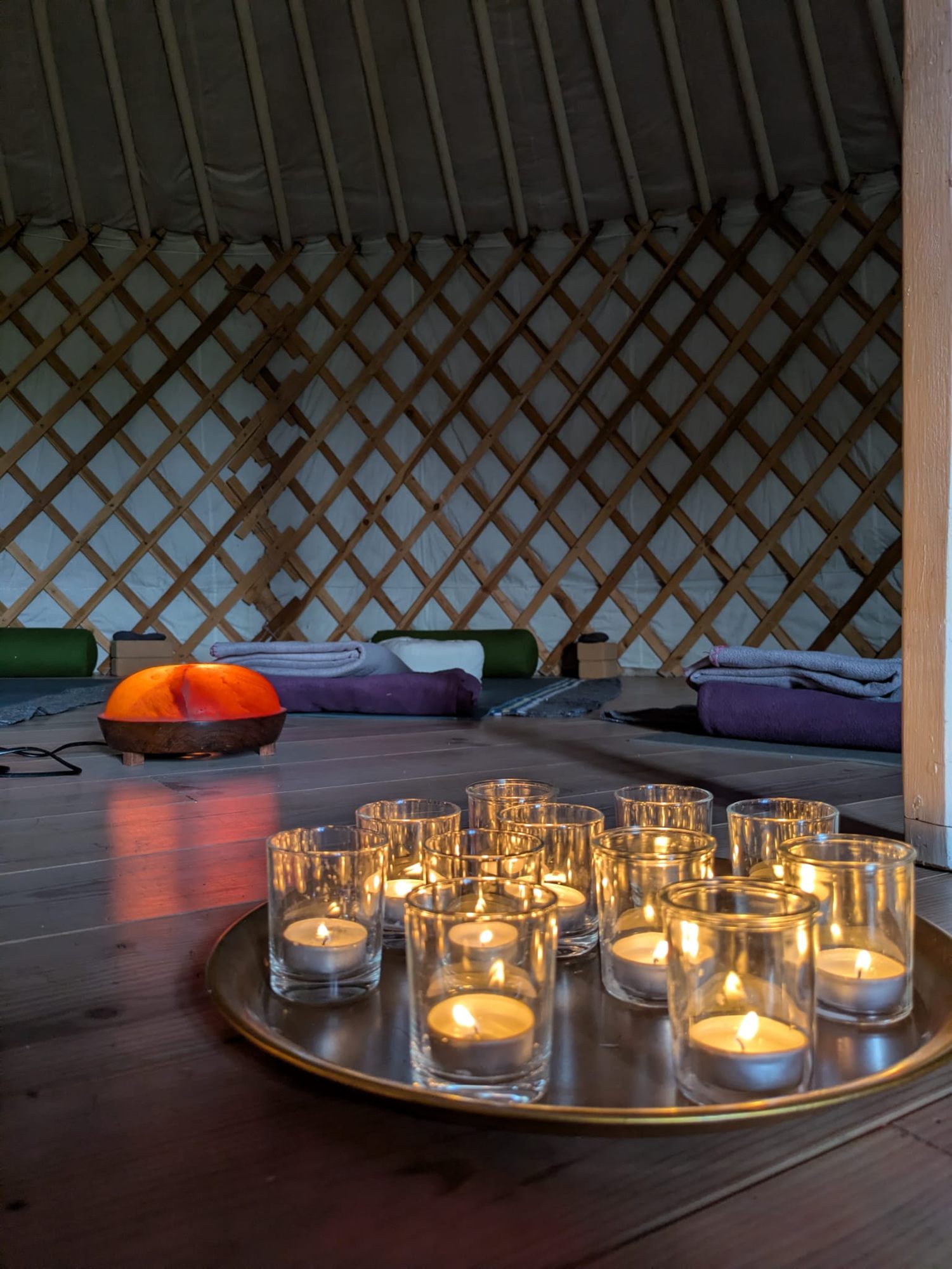 Waxinelichtjes op een koperen schaal in de yurt, met matten en dekens in een kring
